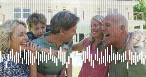 Smiling three-gen family posing in backyard with pool, man in green tee, vertical grid waveform
