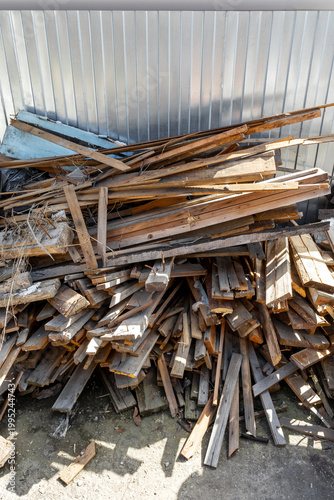 A pile of old wooden planks and construction debris by a metal fence