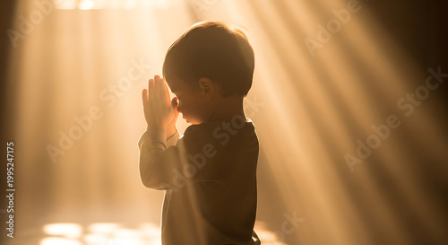 Spiritual concept of a young child praying in golden sunbeams