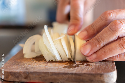 Close-up of Senior Woman Hands Slicing White Onion on Wooden Cutting Board