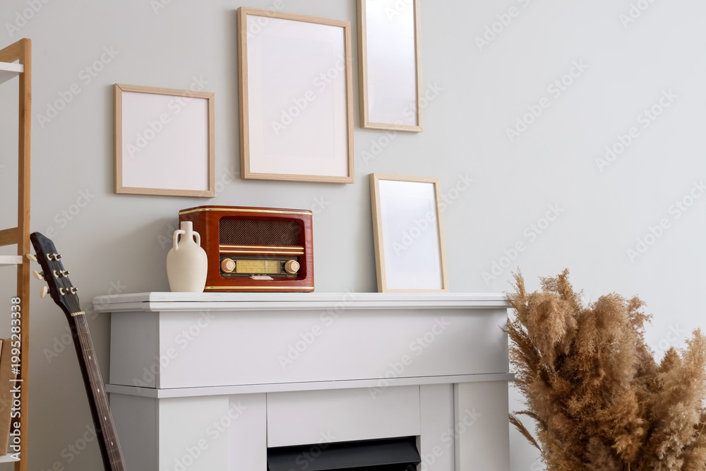 Fototapeta premium Interior of stylish room with frames, pampas grass and retro radio on fireplace