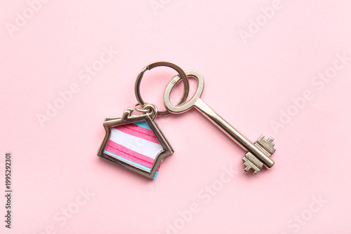 Foto Key with trinket in shape of house and transgender flag on pink background