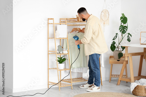 Young man steaming t-shirt ...