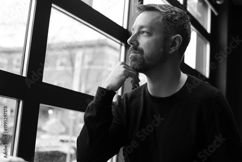 Horizontal black and white portraits of man at a restaurant in Ottawa, Canada. Window-lit lifestyle series with candid expressions, relaxed poses, and modern urban atmosphere.