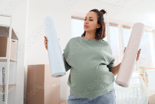 Thoughtful young pregnant woman with wallpapers during repair in children's b...