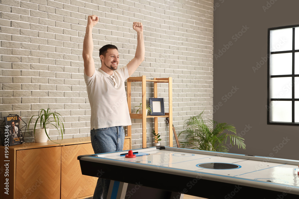 Obraz premium Happy young man playing air hockey at home