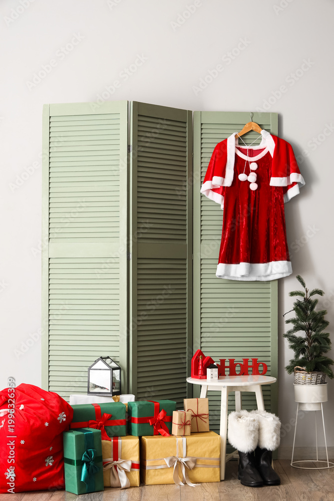 Fototapeta premium Interior of hall with Santa costume on folding screen and Christmas presents