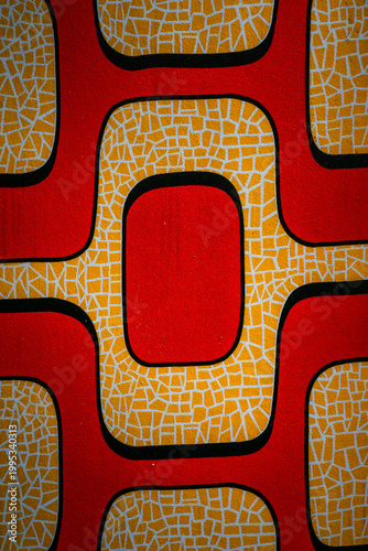Bold red and yellow geometric patterns dominate the frame