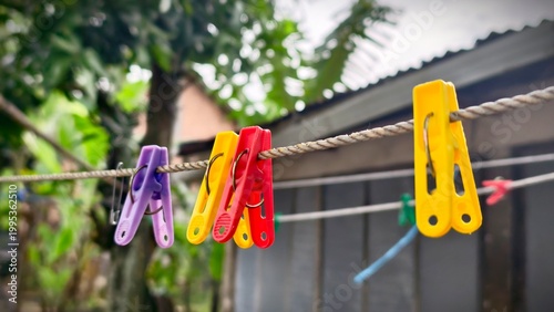 Colorful Plastic Clothes Pegs Hanging on a Clothesline Outdoors.