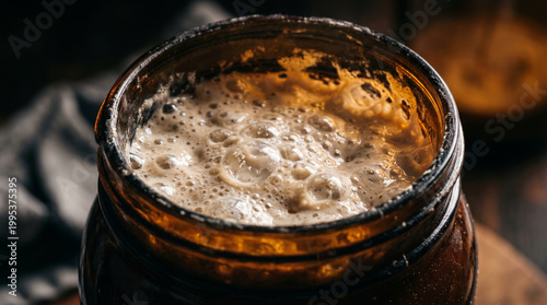 Bubbling active sourdough starter fermenting inside a rustic amber glass jar