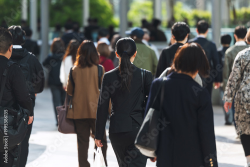 朝、出勤する若い女性の後ろ姿