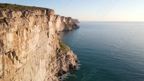 Stunning coastal cliffs overlooking the vast ocean under a clear sky.