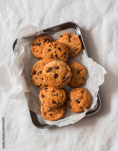 Chocolate drops cookies on a metal tray on a light background , top view