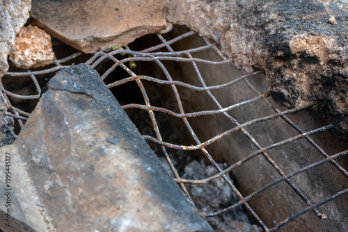 Rusty bent metal wire grate inside a broken clay cooking stove