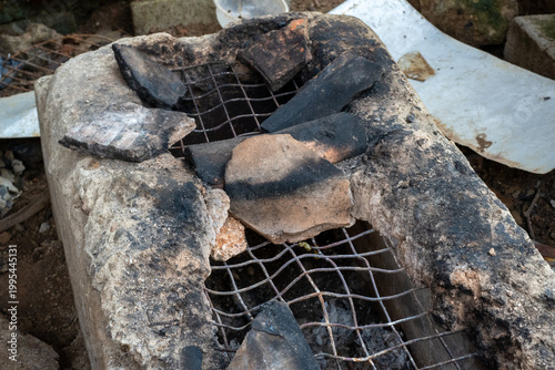 Broken pieces of an old traditional clay stove with a metal grate