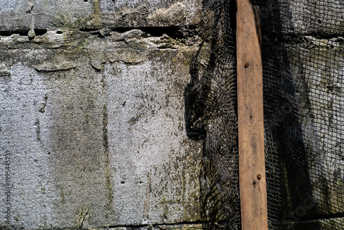 Black mesh and wooden board against a concrete wall