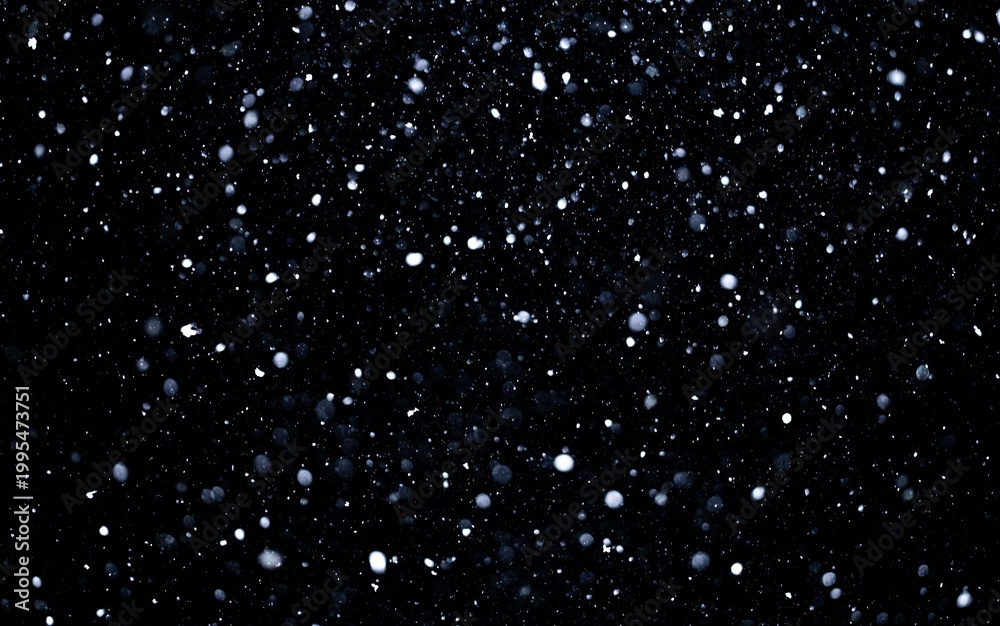 Fototapeta premium Snow particles drifting across black winter background. Snow overlay effect with falling snowflakes. Snow texture overlay with flying snow particles in cold wind. Snowfall layer with snowflakes.