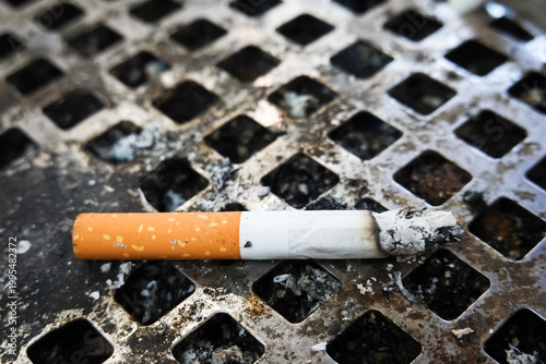 Cigarette butts in metal ashtray with smoke and ash. Burning cigarette butts in ashtray, Smoking concept close-up.