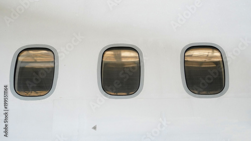Close up of aircraft window with partial view of next window on white fuselage of commercial passenger airplane exterior detail of airplane body parts for aviation industry concept