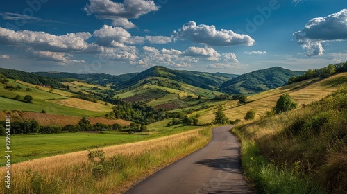 Scenic countryside landscape featuring rolling hills, lush greenery, vibrant farmland, and a peaceful winding road under a blue sky adorned with fluffy clouds