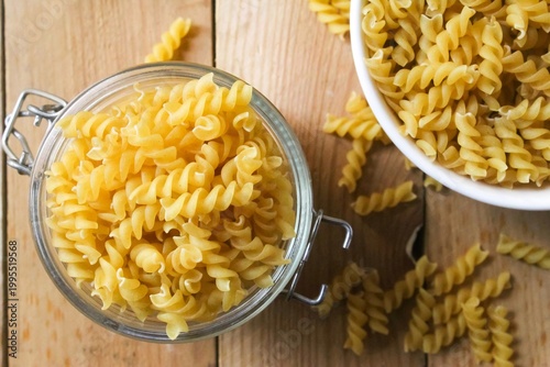 top view of fusilli pasta in a jar and bowl on a wooden table
