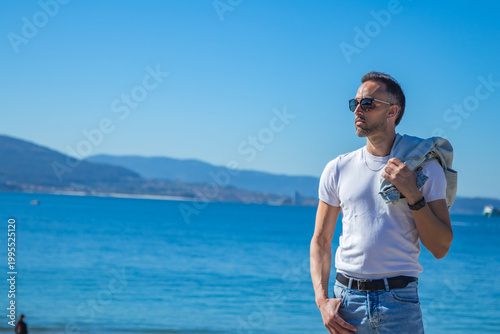 Casual man with jacket over shoulder against a sea background