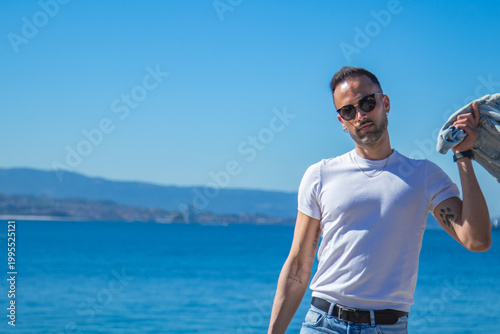casual man looks at camera with jacket on shoulder
