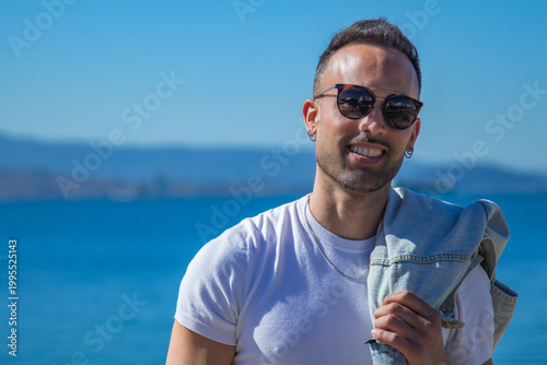 casual man looks at camera with jacket on shoulder