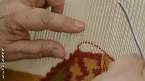 A close-up of hands weaving a colorful traditional carpet on a loom, showcasing intricate craftsmanship and cultural artistry.