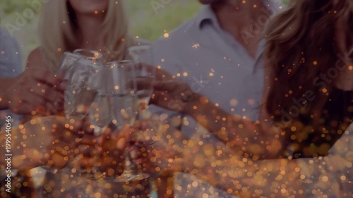 Group raising champagne flutes and clinking for events, golden bokeh overlay enhancing warmth