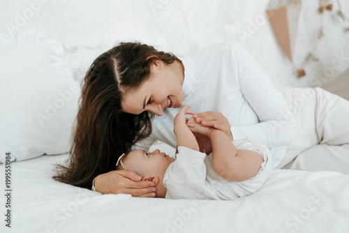 Quadro em tela mother with a baby in her arms, a loving single mother gently hugs and kisses her little child at home, motherly love and care, a happy mother with a baby