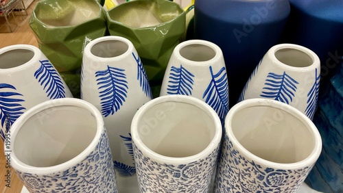 Bild auf Leinwand Collection of ceramic vases with blue leaf patterns and green geometric planters