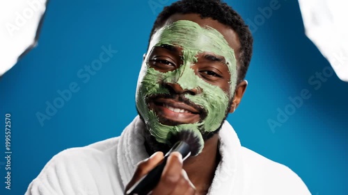 Man Applying Green Face Mask with Brush.