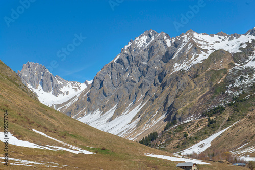 beautiful rocky peak mountains peak at spring with some snow and green meadow...