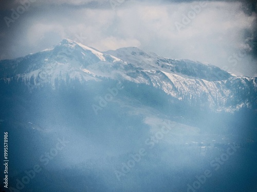 a misty, snow-capped mountain range under a cloudy sky