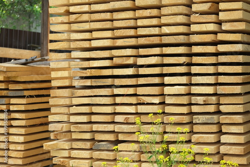 Stack of industrial pine wooden planks in an outdoor sawmill storage.
