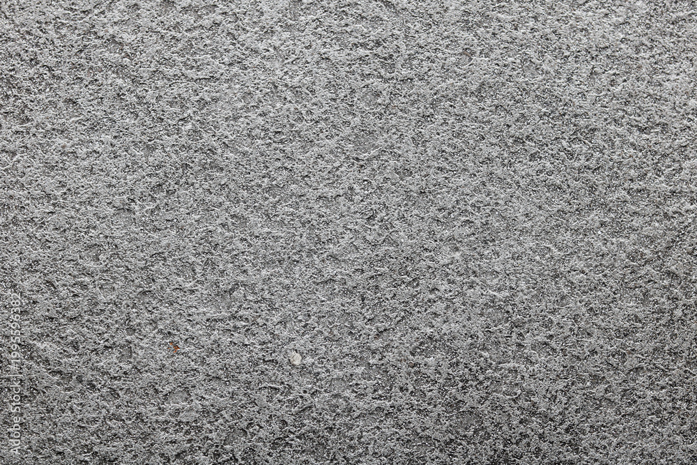 Fototapeta premium A detailed grainy concrete surface. The high-contrast image highlights a rough, porous texture with tiny pebbles and weathered indentations.