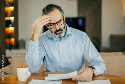 Foto Concerned man dealing with financial stress and debt at home