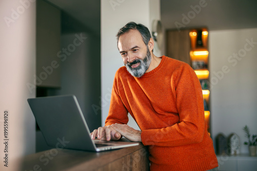 Happy man teleworking using laptop computer at home