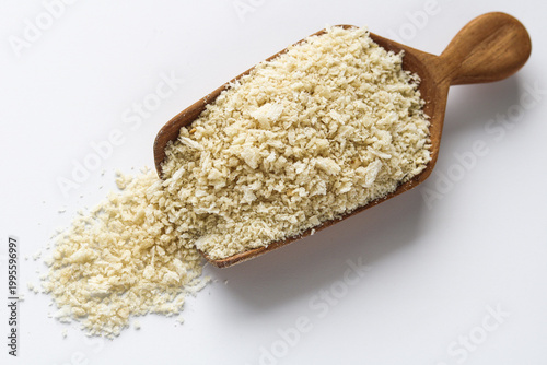 Fotografía Panko bread crumbs spilling from a wooden scoop, isolated on a clean white surface