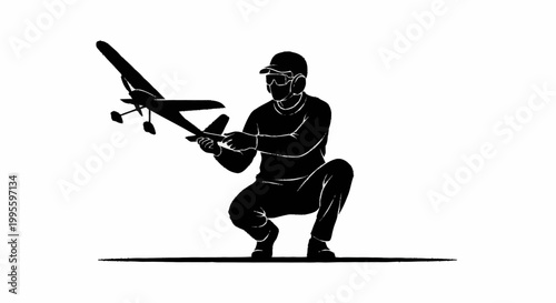 A man in a squatting position holding a small airplane model.