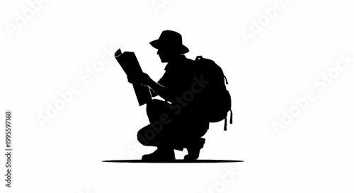 A silhouette of a man crouching down to read a map carefully