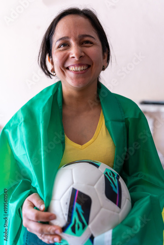 Latin woman celebrating football, holding a soccer ball with a green flag draped