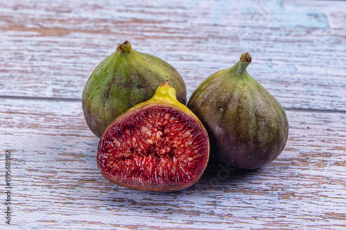 Fresh ripe figs on a rustic background, one cut in half showing red seeds