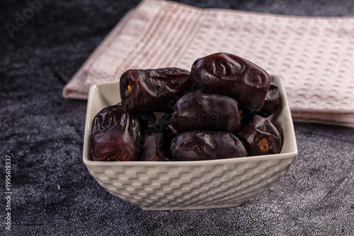 Medjool dates in white bowl on dark grey background