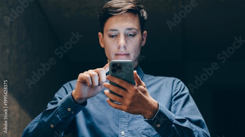 Man using smartphone in dark, textured environment keywords