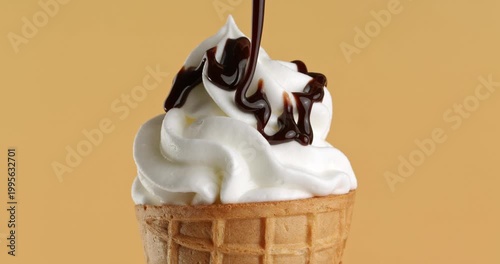 Vanilla ice cream in a waffle cone is drizzled with chocolate glaze. Close-up footage on the rotating table.