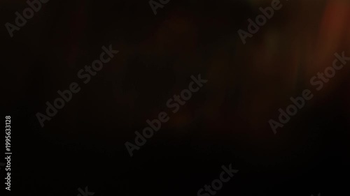 Real warm golden light leak with soft amber bokeh sweeping across dark background. Organic optical lens flare transition overlay for cinematic music video intro and title sequence.