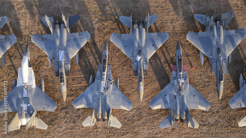 Tucson, United States - 30 January 2025: Aerial view of numerous powerful gray fighter jets starkly contrasted against the warm, sun-drenched desert earth.
