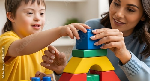 Woman therapist helping child with Down syndrome playing with colorful building blocks. Inclusion and education development concept. Supportive session for kid learning through creative game.